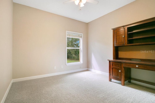 unfurnished office with a ceiling fan, baseboards, and light carpet