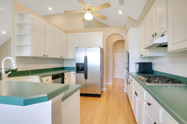 kitchen with open shelves, arched walkways, a sink, under cabinet range hood, and appliances with stainless steel finishes