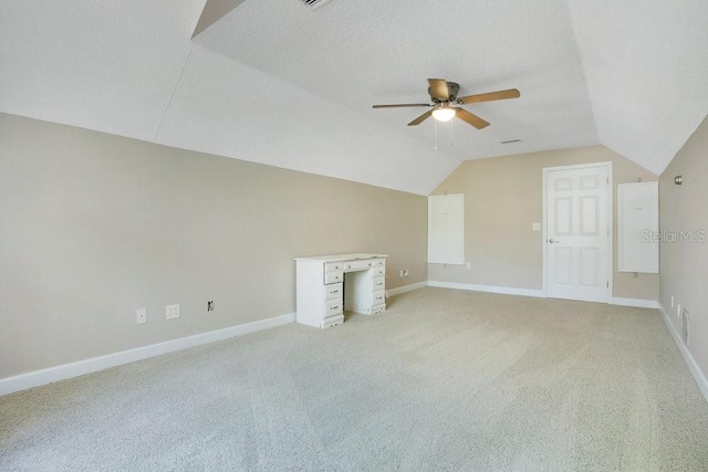 additional living space featuring a textured ceiling, lofted ceiling, baseboards, and ceiling fan