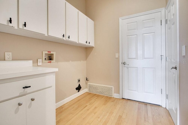 laundry area featuring hookup for a washing machine, visible vents, baseboards, light wood-style flooring, and cabinet space