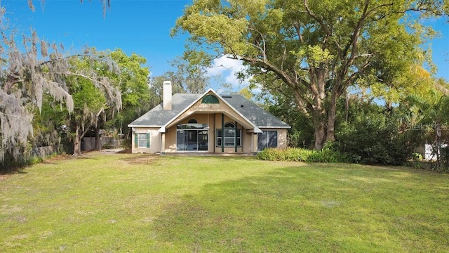 rear view of property featuring a yard, a chimney, and fence