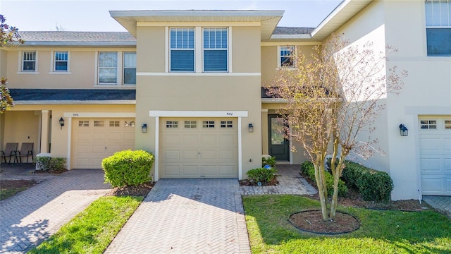 multi unit property featuring decorative driveway, a garage, and stucco siding