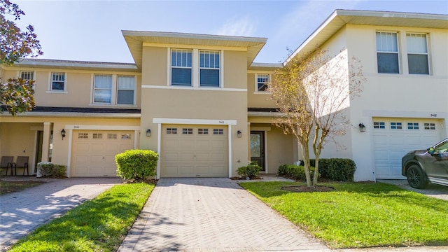 townhome / multi-family property featuring stucco siding, decorative driveway, and a garage