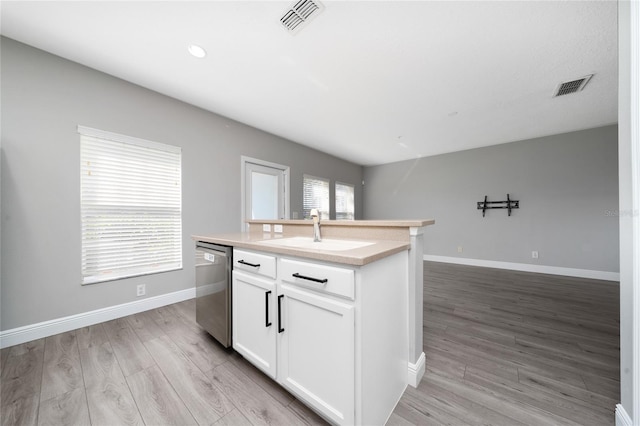 kitchen featuring visible vents, light wood-style flooring, a sink, stainless steel dishwasher, and open floor plan