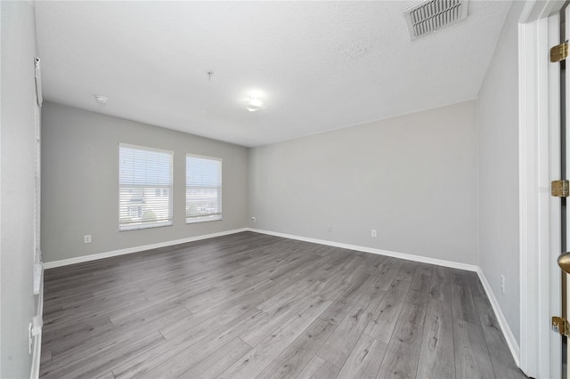 spare room with visible vents, baseboards, and wood finished floors