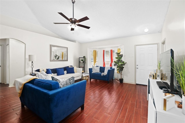 living room with dark wood-style floors, arched walkways, a ceiling fan, and vaulted ceiling