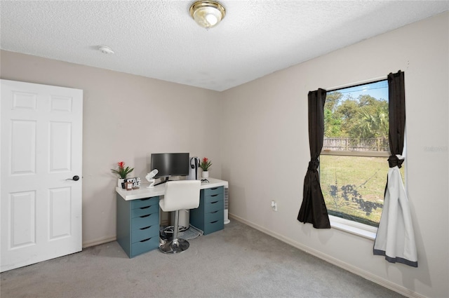 home office featuring a textured ceiling, baseboards, and light carpet