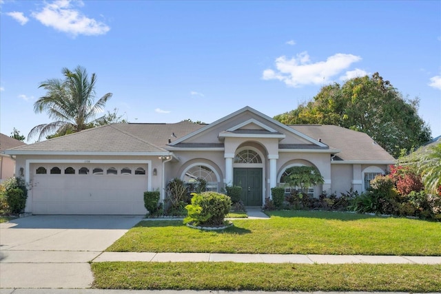 view of front of property featuring stucco siding, driveway, an attached garage, and a front yard