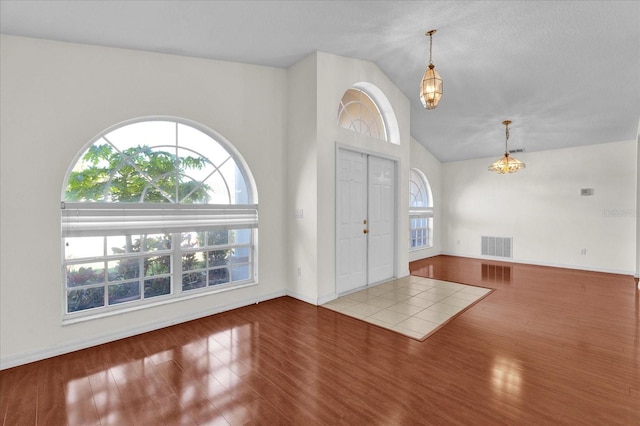 entrance foyer featuring lofted ceiling, wood finished floors, and visible vents