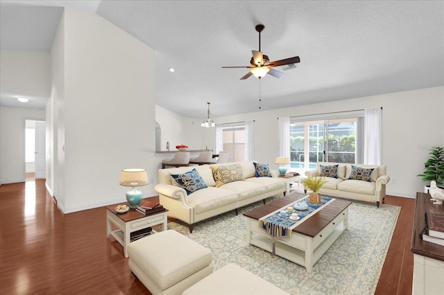 living area featuring ceiling fan with notable chandelier, baseboards, lofted ceiling, and wood finished floors