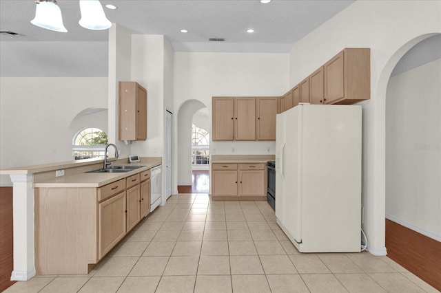 kitchen with a wealth of natural light, visible vents, light brown cabinets, a sink, and white appliances