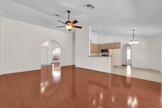 unfurnished living room featuring visible vents, arched walkways, light wood-style floors, and a ceiling fan