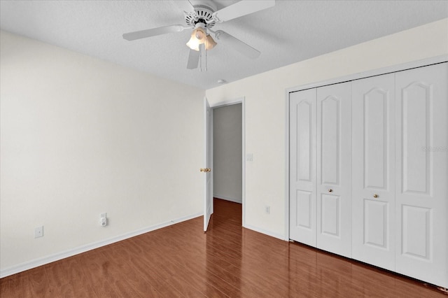 unfurnished bedroom with wood finished floors, baseboards, ceiling fan, a closet, and a textured ceiling