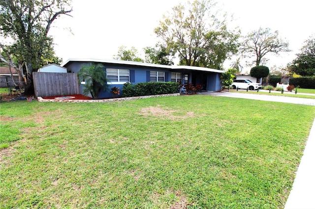 ranch-style house featuring an attached carport, concrete driveway, fence, and a front lawn