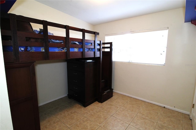 bedroom with light tile patterned flooring and baseboards