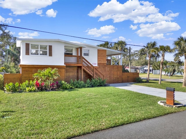 view of front of house featuring a front yard, stairway, fence, and stucco siding