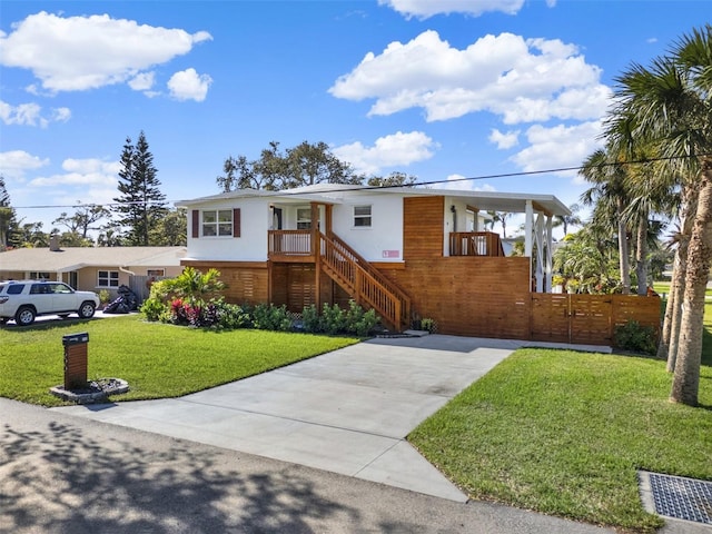 view of front of house featuring a front lawn, fence, driveway, and stucco siding