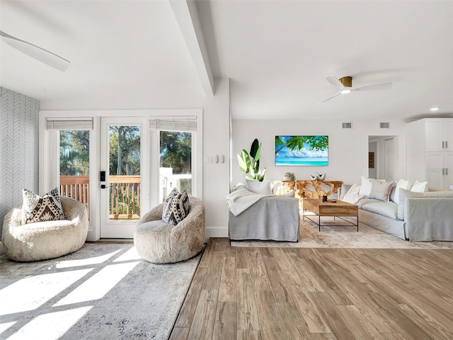 living room with visible vents, wood finished floors, and a ceiling fan