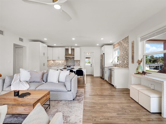 living room with a wealth of natural light, visible vents, light wood-style flooring, and recessed lighting