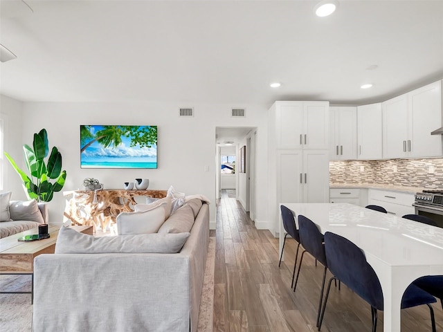 living room featuring light wood-style flooring, recessed lighting, visible vents, and baseboards