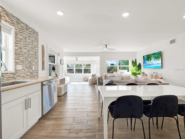 kitchen featuring tasteful backsplash, visible vents, dishwasher, light wood-style flooring, and white cabinetry