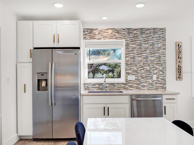 kitchen featuring decorative backsplash, white cabinets, appliances with stainless steel finishes, and a sink