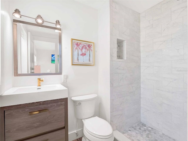 full bathroom with baseboards, toilet, vanity, and a tile shower