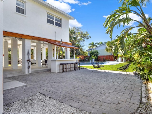 view of home's community featuring a swimming pool, a patio, outdoor dry bar, and fence