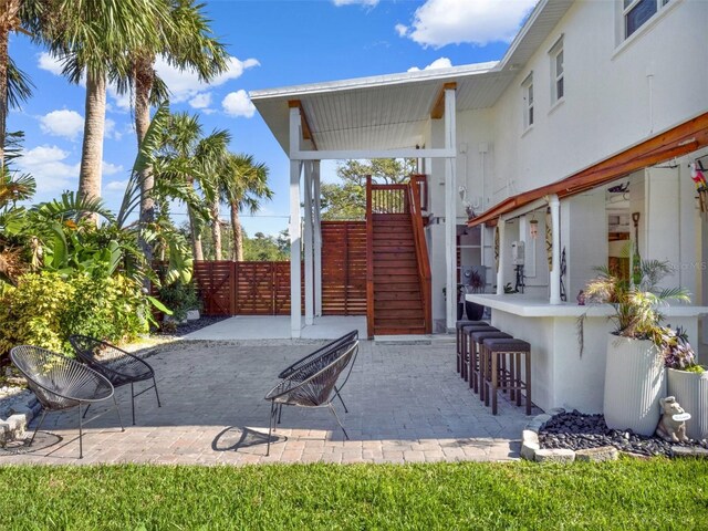 view of patio with stairway, outdoor dry bar, and fence