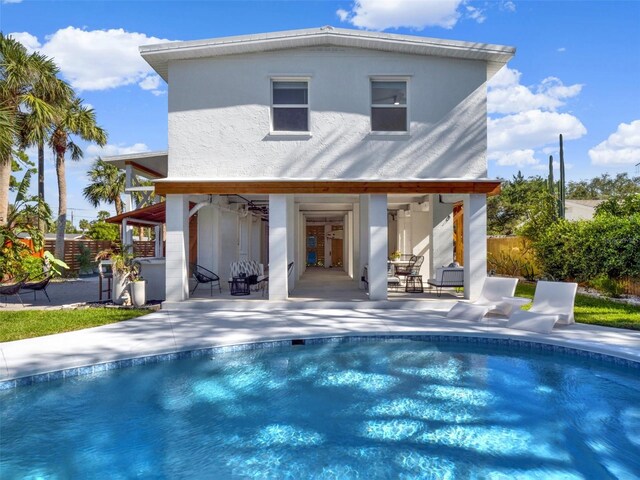 rear view of house featuring a patio, a fenced in pool, fence, driveway, and a garage