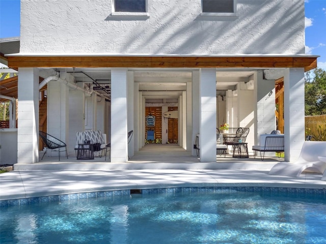 rear view of property with an outdoor pool, stucco siding, and a patio area