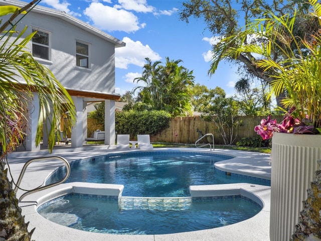 view of pool with a patio area, a pool with connected hot tub, and fence