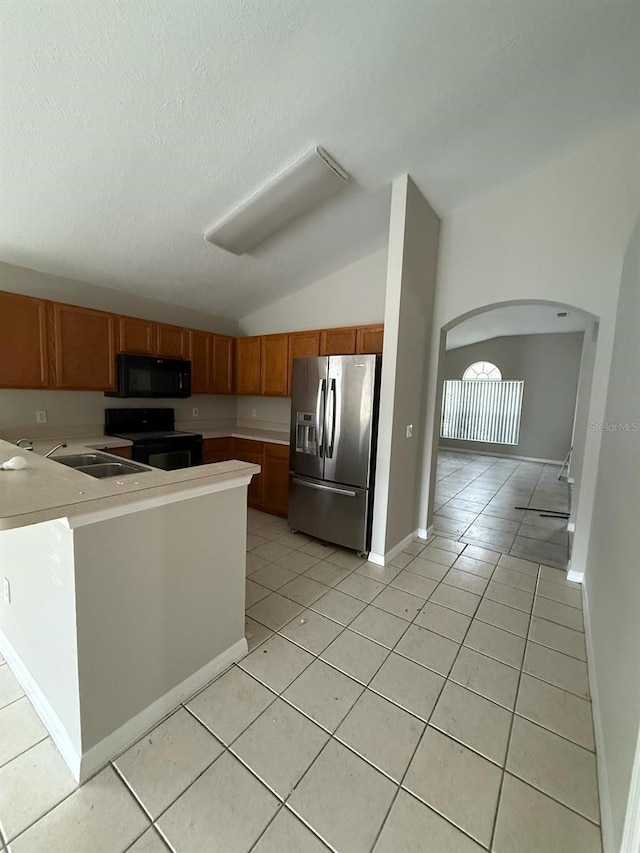 kitchen featuring black appliances, a sink, light countertops, light tile patterned floors, and lofted ceiling