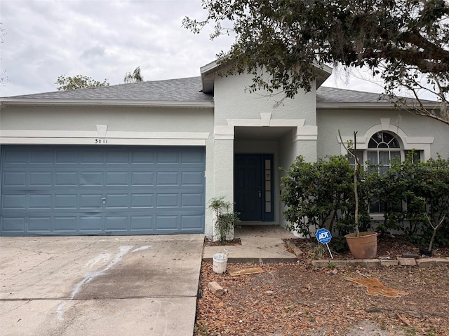 view of front of house with stucco siding, concrete driveway, a garage, and roof with shingles