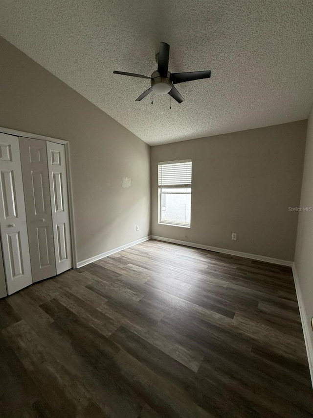 unfurnished bedroom with baseboards, a textured ceiling, wood finished floors, and vaulted ceiling