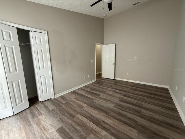 unfurnished bedroom with a closet, baseboards, a textured ceiling, and dark wood finished floors