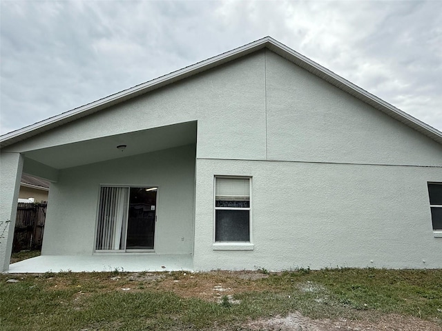 rear view of property with stucco siding and fence