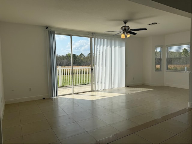 tiled empty room featuring a ceiling fan, baseboards, and visible vents