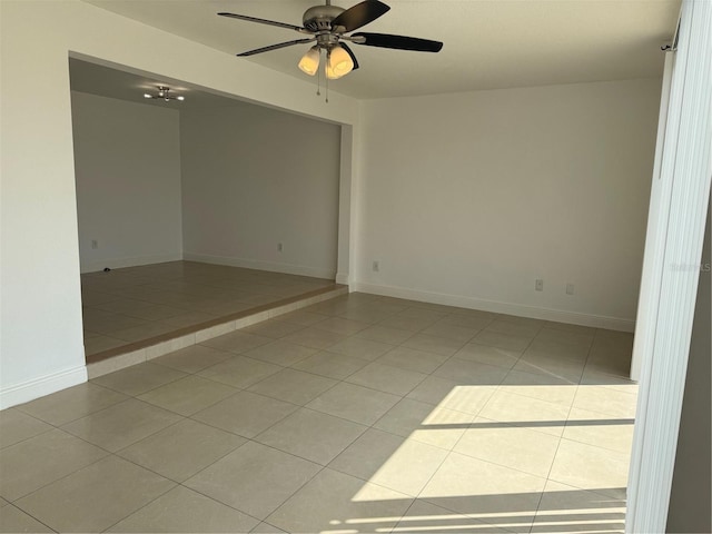 unfurnished room with light tile patterned floors, a ceiling fan, and baseboards