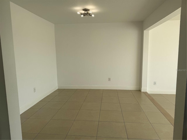 unfurnished room with tile patterned flooring and baseboards