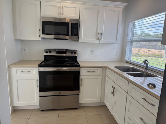 kitchen featuring light countertops, light tile patterned floors, stainless steel appliances, white cabinetry, and a sink