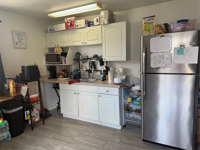 kitchen with light countertops, white cabinets, appliances with stainless steel finishes, and a sink