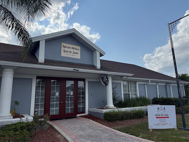 view of front facade featuring stucco siding and roof with shingles