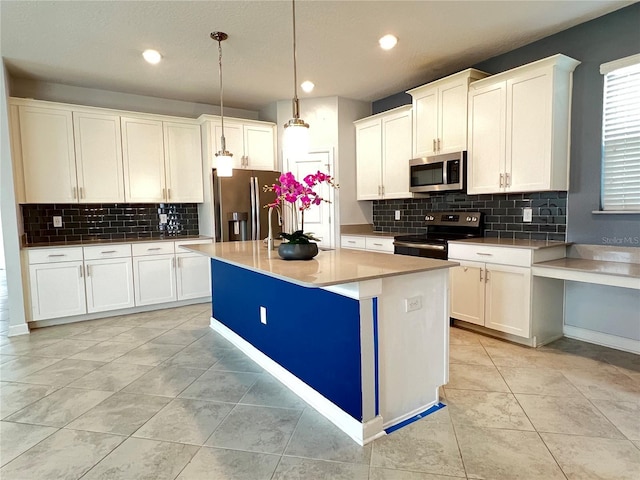 kitchen featuring backsplash, decorative light fixtures, an island with sink, stainless steel appliances, and white cabinetry