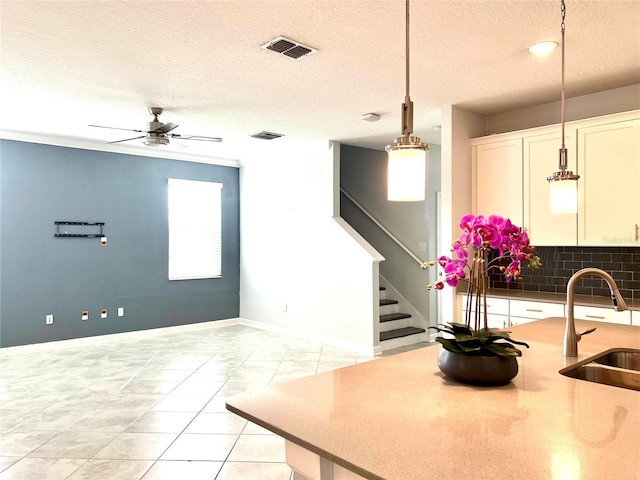 kitchen featuring a sink, visible vents, white cabinets, and decorative light fixtures