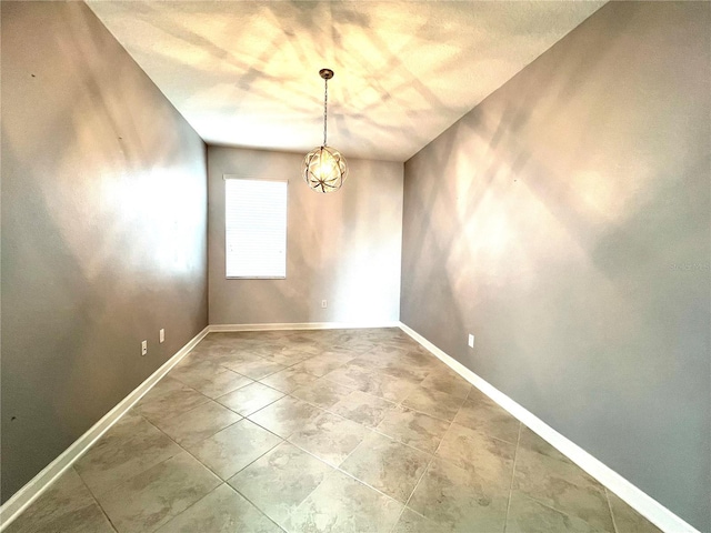 spare room with an inviting chandelier and baseboards