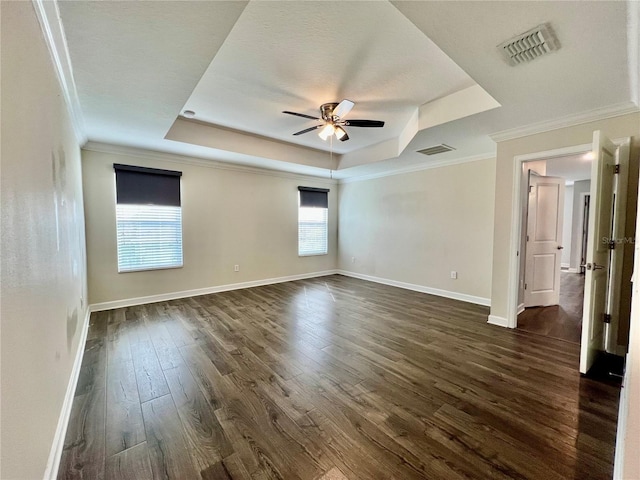 spare room featuring visible vents, a raised ceiling, baseboards, and dark wood-style floors