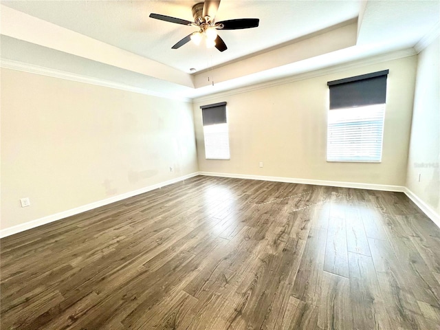 spare room with a tray ceiling, baseboards, and dark wood-style flooring