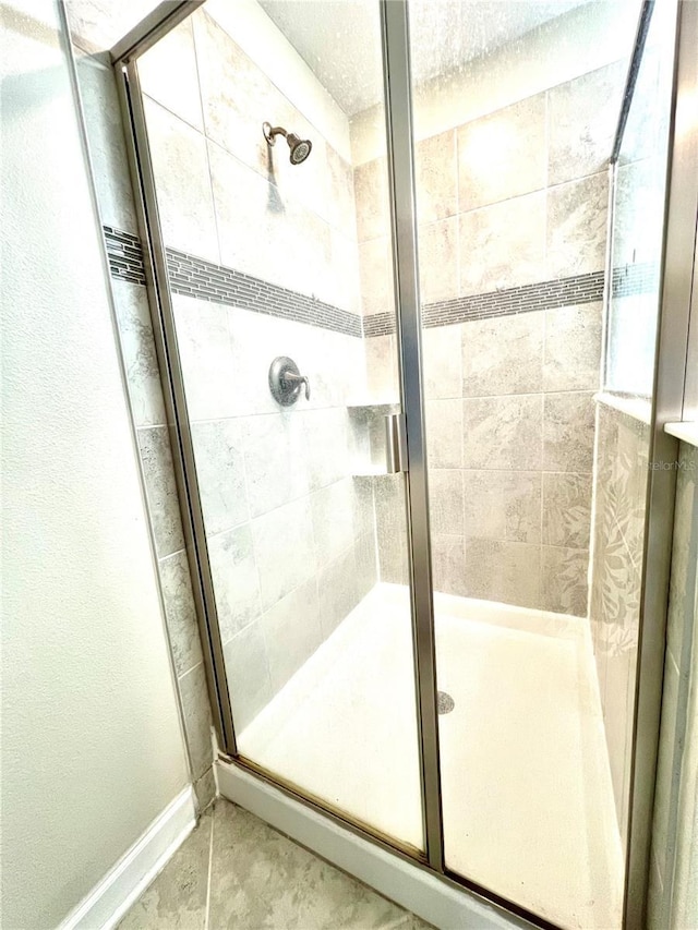 bathroom featuring tile patterned floors, a stall shower, and baseboards