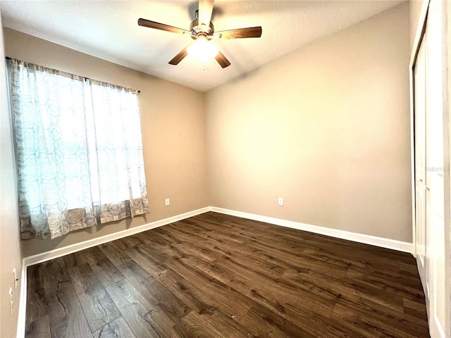 empty room featuring baseboards, dark wood-style floors, and a ceiling fan